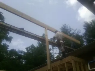 Carpenter setting a ridge beam over a new addition frame — Ice Dam Removal by Roofing Brothers in Mabank