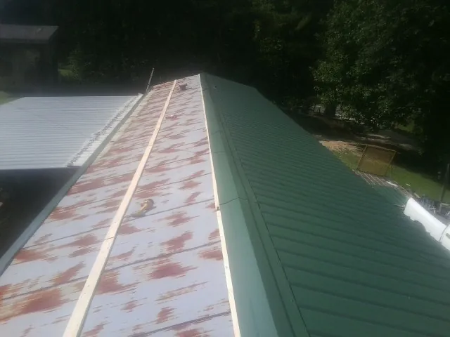 Old rusted panels beside newly installed green metal roofing — Wind Damage Roof Repair by Roofing Brothers in Mabank