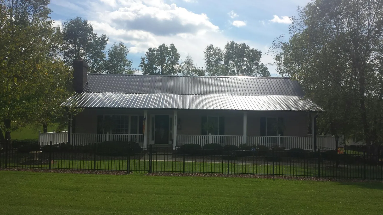Gray metal roof on a brick ranch with a full width front porch — Gutter Guard Installation work by our crew in Mabank