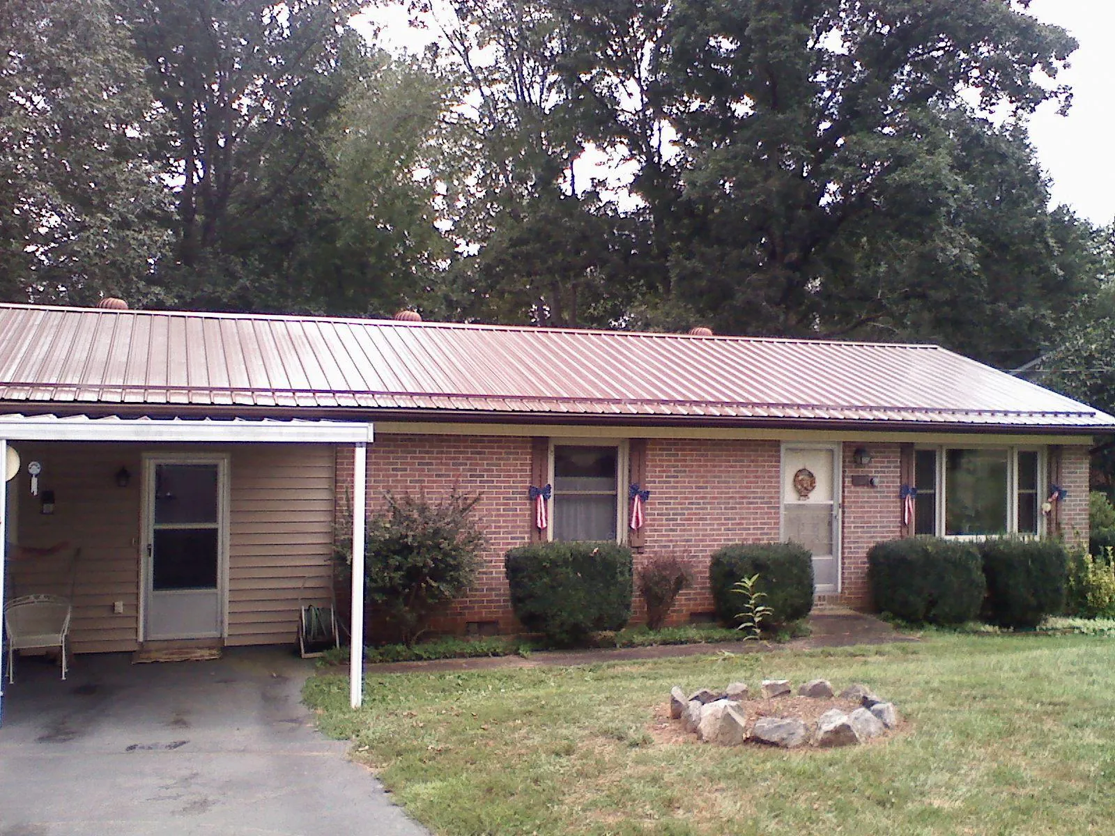 Bronze metal roof and carport on a brick ranch home — Roof Repair work by our crew in Mabank