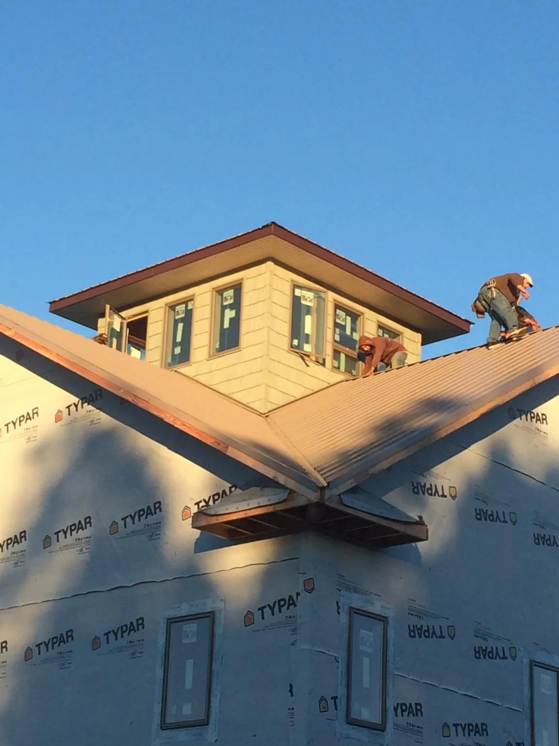 Roofers working around a rooftop cupola on a new metal roof at sunset — Roof Waterproofing in Mabank by Roofing Brothers